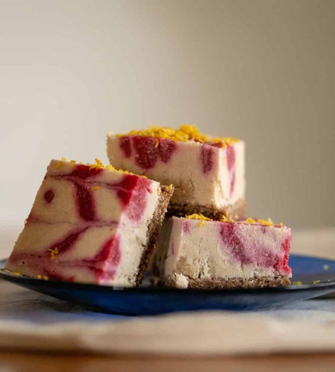 Raw vegan raspberry cheesecake squares on blue plate